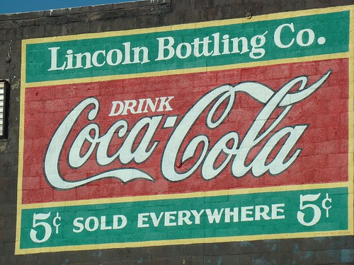 Mural text says "Lincoln Bottling Co. Drink Coca-Cola. 5 cents. Sold everywhere."