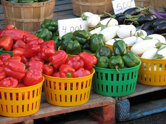 Baskets of red and green peppers in a market place. 