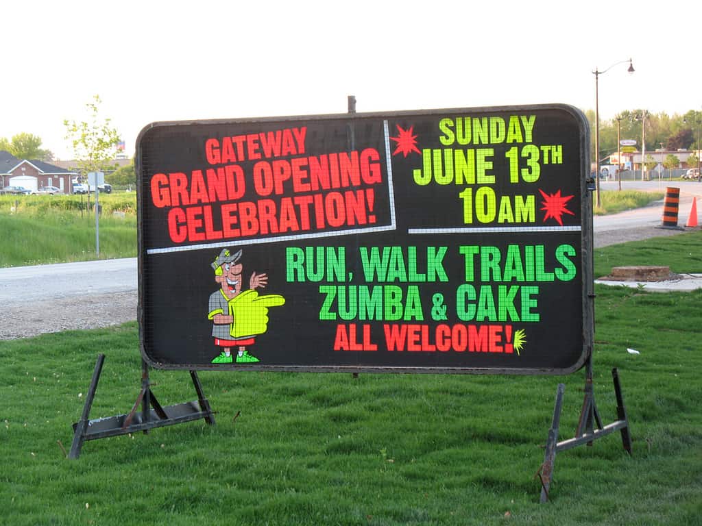 Business sign for a grand opening includes zumba and cake.