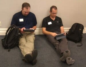 Two people seated on the floor, using iPads to work. 
