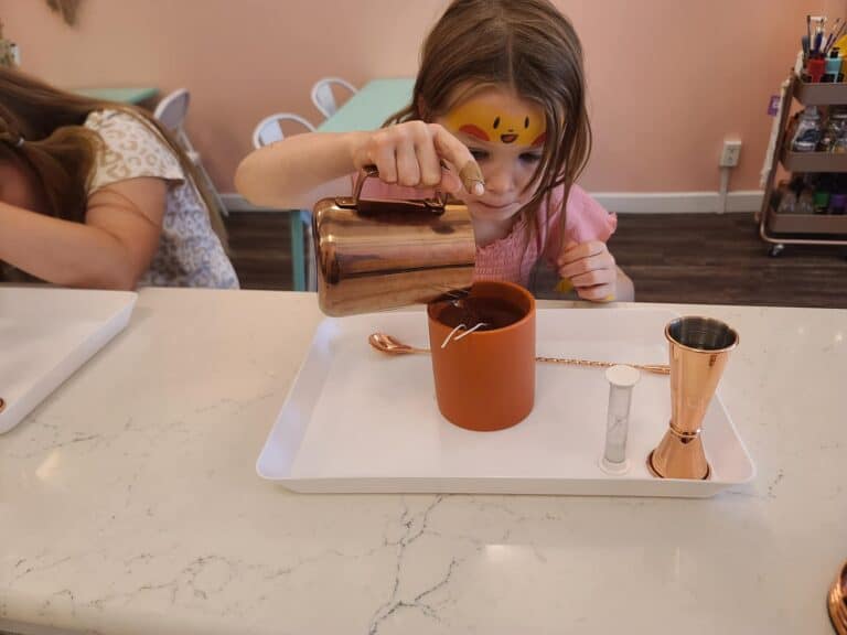 A young girl carefully pours her own candle.