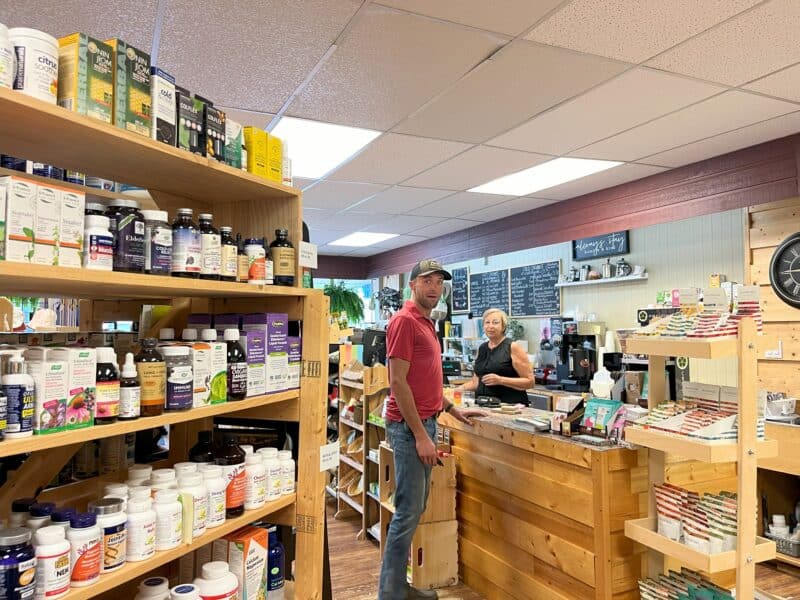 A young man shopping in a wellness store with packed shelves. 