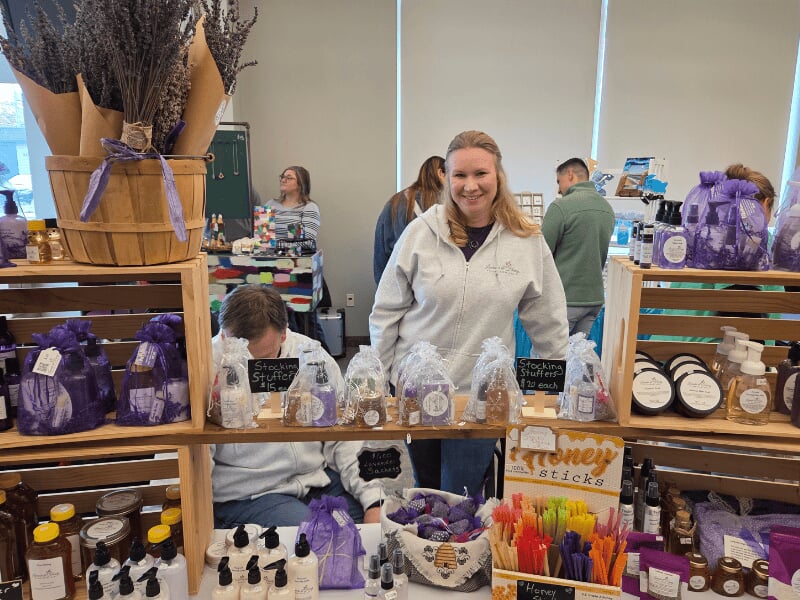 local microbusiness owner selling handmade lavender and honey products at a small town vendor market booth